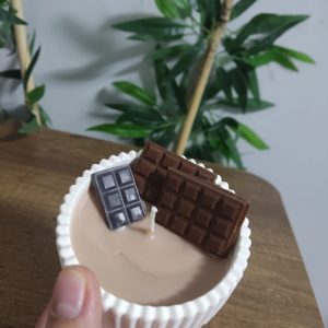 Çikolata kokulu el yapımı soya mumu: beyaz oluklu kapta sütlü kahve rengi mum, üzerinde iki adet el dökümü çikolata tableti