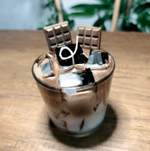 Iced chocolate coffee mum: cam bardakta sütlü kahve katmanları, jel wax buz küpleri ve iki adet çikolata tableti figürü