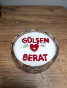 Kişiye özel isimli mum: kristal cam kapta beyaz soya mumu, üzerinde kırmızı harflerle iki isim ve aralarında kırmızı kalp figürü