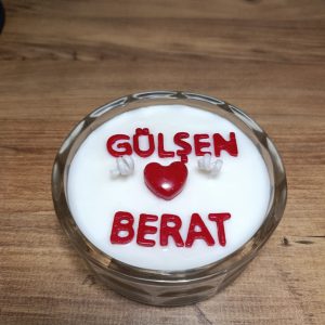 Kişiye özel isimli mum: kristal cam kapta beyaz soya mumu, üzerinde kırmızı harflerle iki isim ve aralarında kırmızı kalp figürü